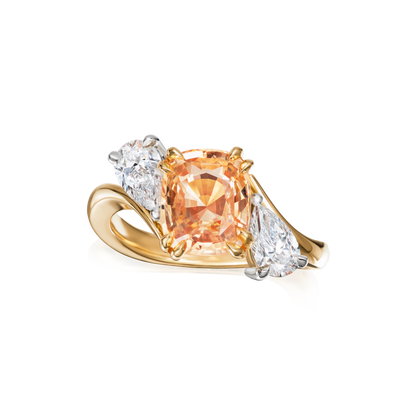 Gold ring with a peach-colored gemstone and two smaller clear stones on a white background