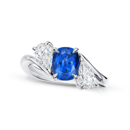 Ring with a blue gemstone and pear-shaped diamonds on a white background