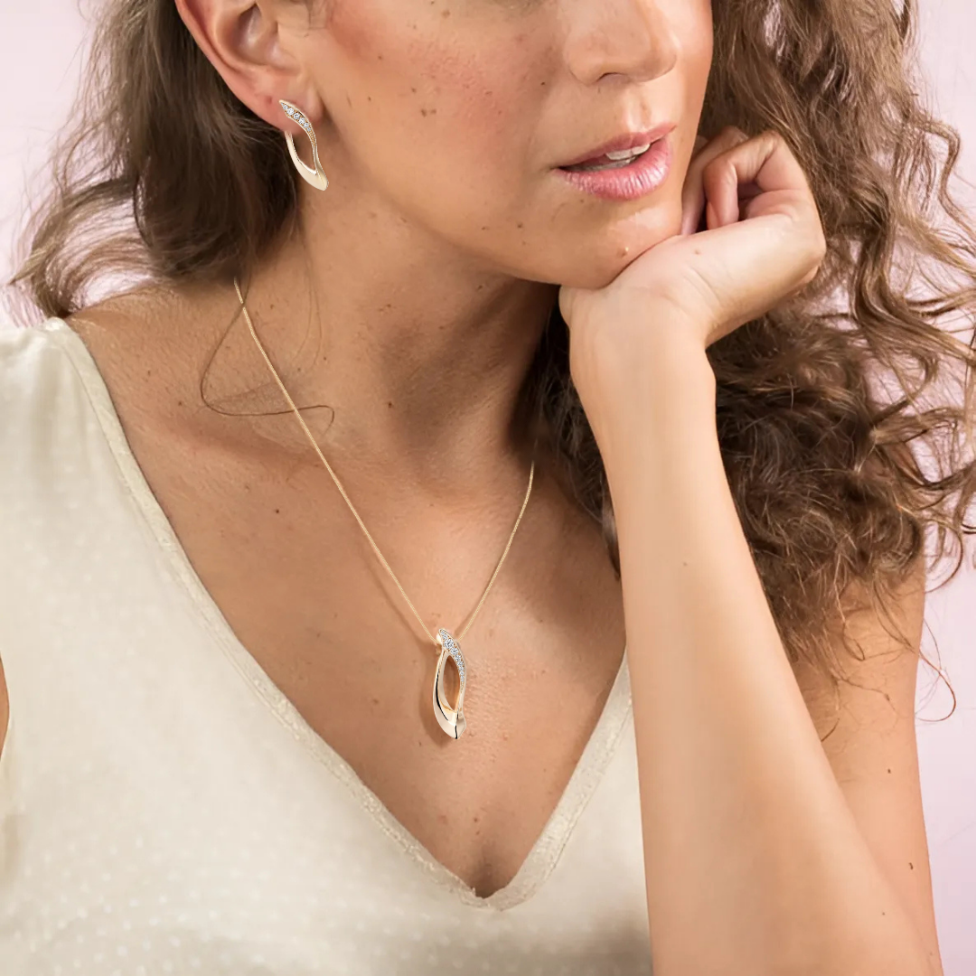 Woman wearing a gold necklace with a pendant on a plain background