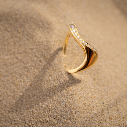 Gold ring with diamonds on a sandy surface