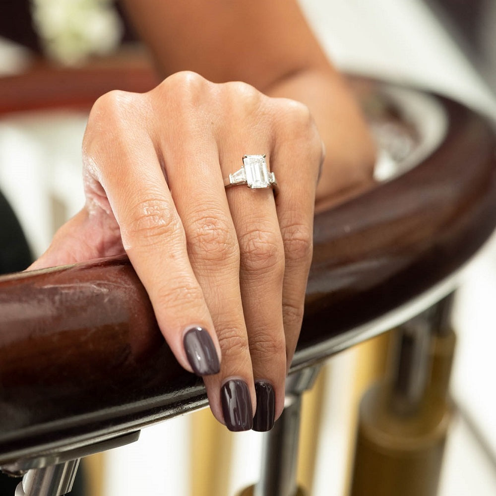 Hand wearing a diamond ring on a blurred background